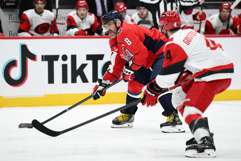 Washington Capitals left wing Alex Ovechkin (8) skates with the puck against Carolina Hurricanes defenseman Shayne Gostisbehere (4) during the first period of an NHL hockey game, Thursday, Dec. 11, 2025, in Washington. (AP Photo/Nick Wass)