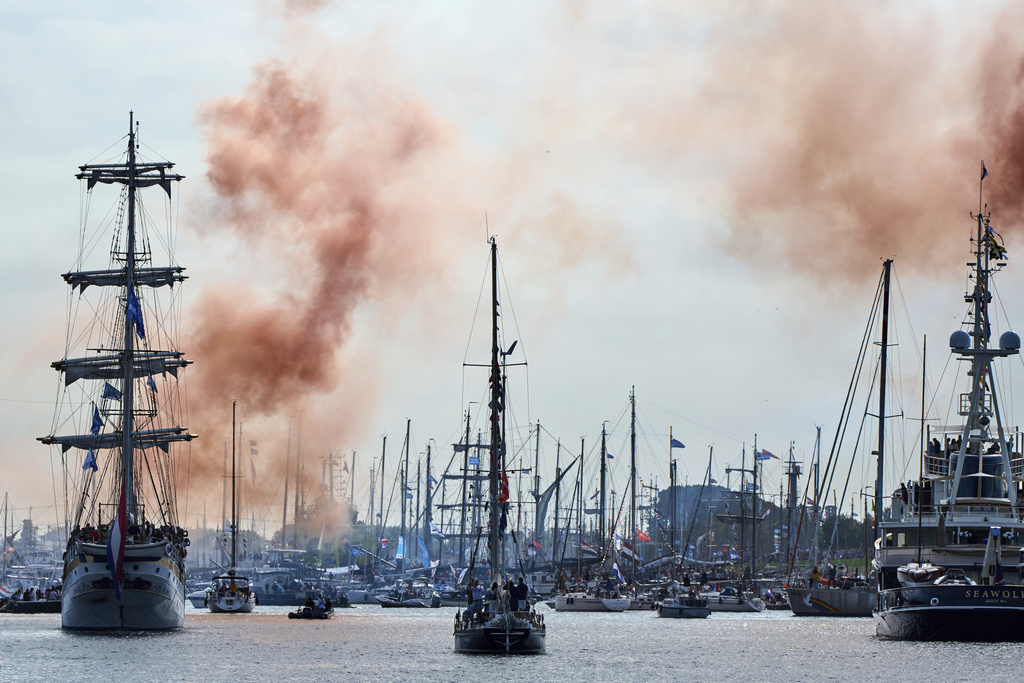 Orange smoke signals the start of the parade of hundreds of tall ships sailing into the Dutch capital's harbor for the 10th edition of SAIL, in Amsterdam, Netherlands, Wednesday, Aug. 20, 2025. (AP Photo/Peter Dejong)