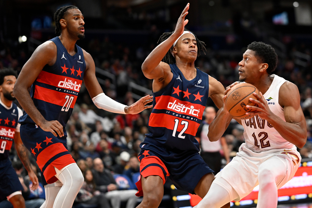 Cleveland Cavaliers forward De'Andre Hunter (12) attempts to make a shot against Washington Wizards guard Tre Johnson (12) and Wizards center Alex Sarr during the first half of an NBA Cup basketball game, Friday, Nov. 7, 2025, in Washington. (AP Photo/John McDonnell)