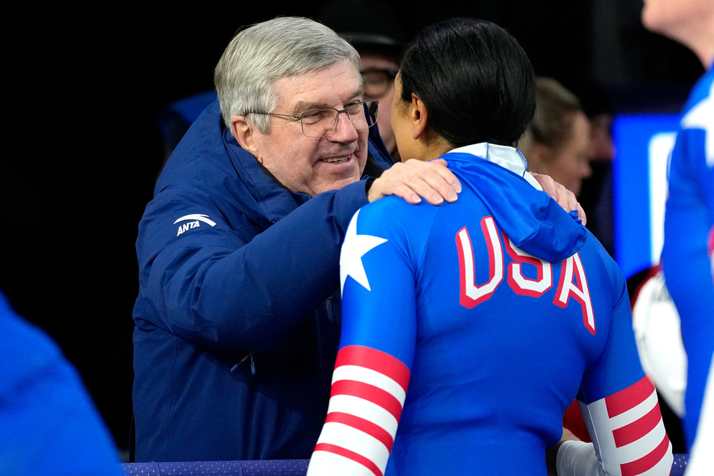 Former IOC President Thomas Bach, left, talks to United States' Elana Meyers Taylor at the finish during a two women bobsled run at the 2026 Winter Olympics, in Cortina d'Ampezzo, Italy, Friday, Feb. 20, 2026. (AP Photo/Alessandra Tarantino)