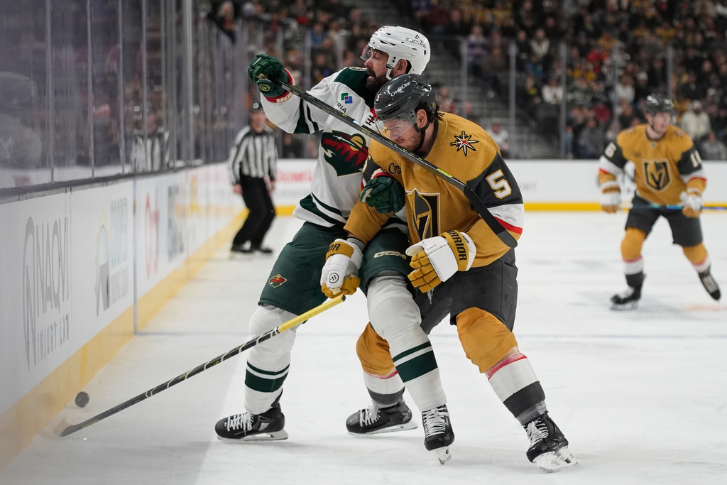 Minnesota Wild defenseman Jake Middleton, left, and Vegas Golden Knights defenseman Jeremy Lauzon battle for the puck during the first period of an NHL hockey game Monday, Dec. 29, 2025, in Las Vegas. (AP Photo/John Locher)
