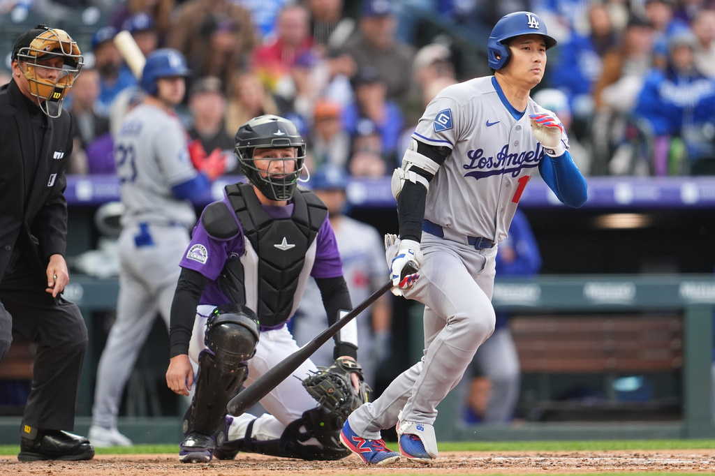Los Angeles Dodgers two-way player Shohei Ohtani, right, grounds out as Colorado Rockies catcher Hunter Goodman, center, and home plate umpire Dan Issogna, left, look on in the third inning of a baseball game Saturday, April 18, 2026, in Denver. (AP Photo/David Zalubowski)