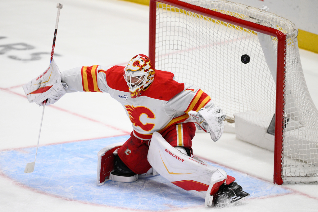 A puck shot by Washington Capitals center Justin Sourdif, not shown, gets past Calgary Flames goaltender Devin Cooley (1) for a goal during the third period of an NHL hockey game, Monday, March 9, 2026, in Washington. (AP Photo/Nick Wass)