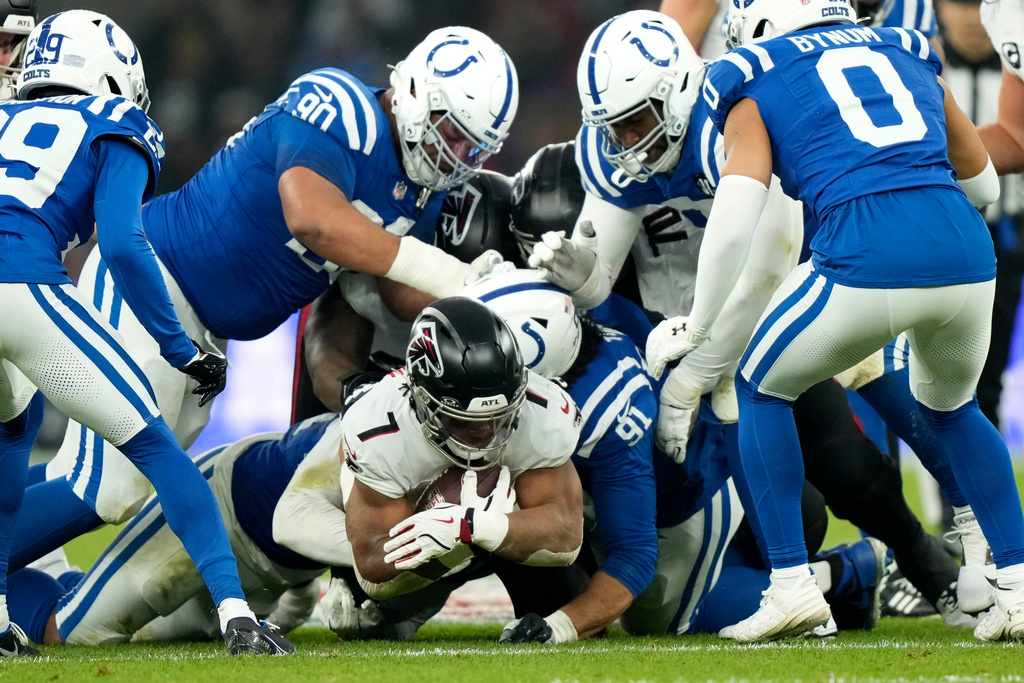 Atlanta Falcons running back Bijan Robinson (7) is tackled by Indianapolis Colts defensive end JT Tuimoloau (91) during the first half of an NFL football game, Sunday, Nov. 9, 2025, in Berlin, Germany. (AP Photo/Ebrahim Noroozi)