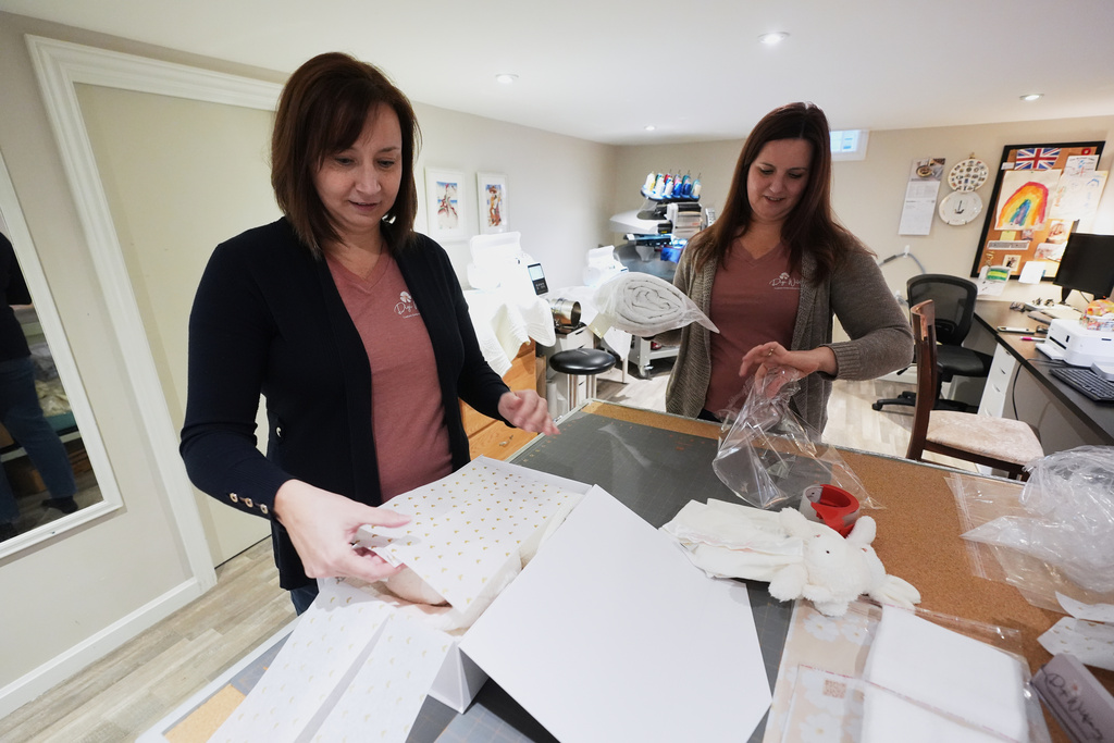 Fran Poirier, left, and her sister, Sue Bacarro, right, fill orders at their Etsy shop Digi Wildflowers, Thursday, Oct. 30, 2025, in Windsor, Ontario, Canada. (AP Photo/Paul Sancya)