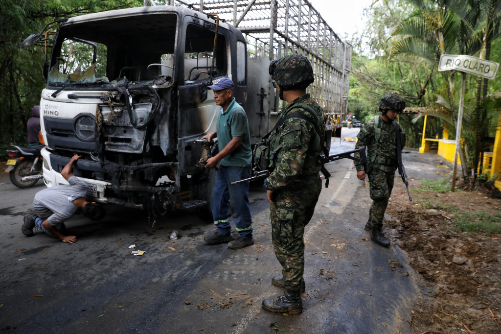 Soldiers stand next to a truck carrying chickens that was set on fire by dissident factions of the former FARC rebels in Jamundi, Colombia, Monday, April 27, 2026. (AP Photo/Santiago Saldarriaga)
