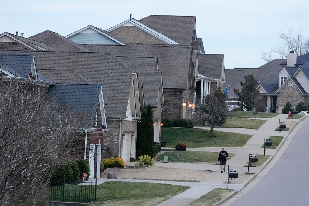 A person walks past single family homes, Tuesday, Feb. 10, 2026, in Nashville, Tenn. (AP Photo/George Walker IV)