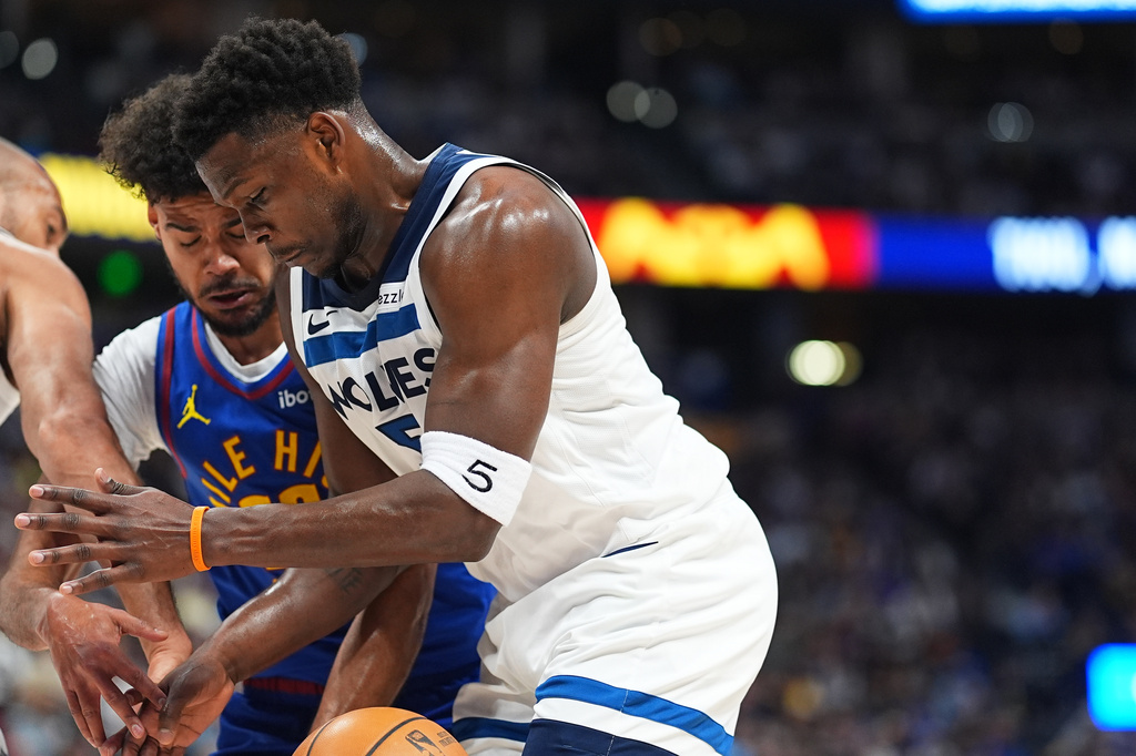 Minnesota Timberwolves guard Anthony Edwards, front, struggles to control the ball as Denver Nuggets forward Cameron Johnson defends in the first half of an NBA basketball game Sunday, March 1, 2026, in Denver. (AP Photo/David Zalubowski)