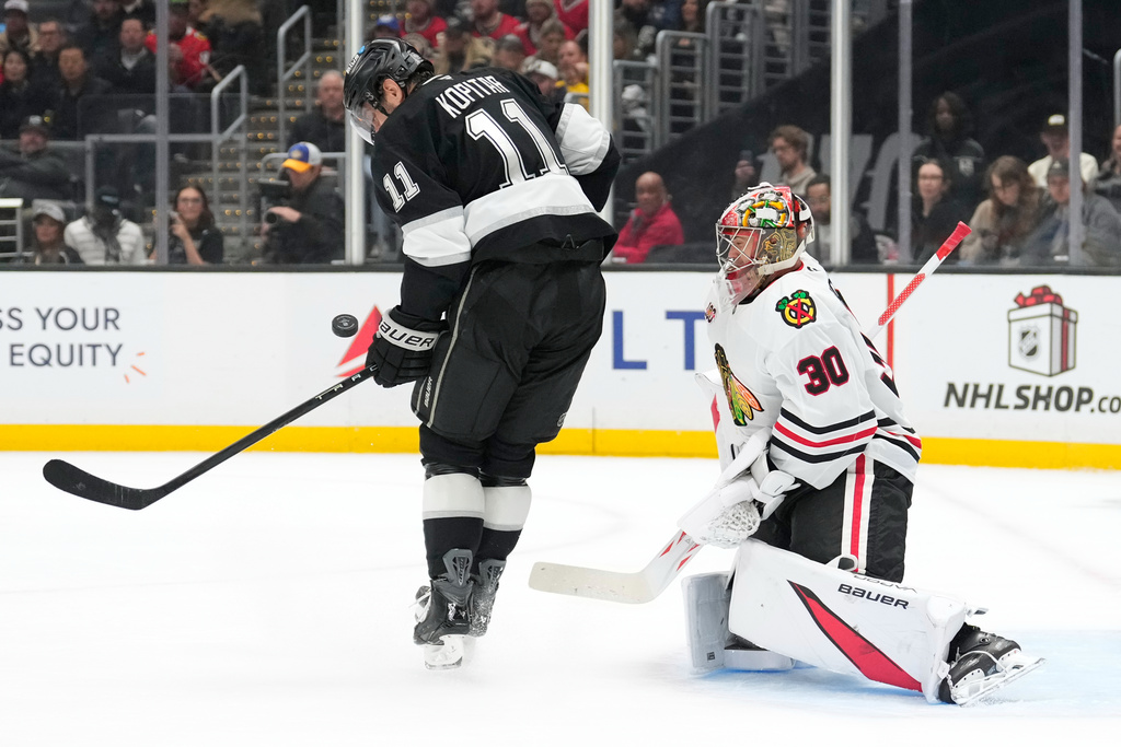 Los Angeles Kings center Anze Kopitar, left, tries to tip a shot past Chicago Blackhawks goaltender Spencer Knight during the second period of an NHL hockey game Thursday, Dec. 4, 2025, in Los Angeles. (AP Photo/Mark J. Terrill)