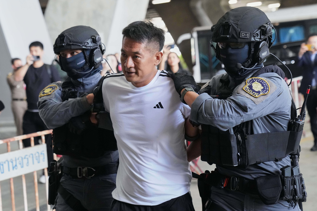 She Zhijiang, an alleged transnational crime kingpin accused by Beijing of having run illegal online gambling operations, is escorted by police at Suvarnabhumi International Airport in Thailand's Samut Prakarn province ahead of being extradited to China, Wednesday, Nov. 12, 2025. (AP Photo/Sakchai Lalit)