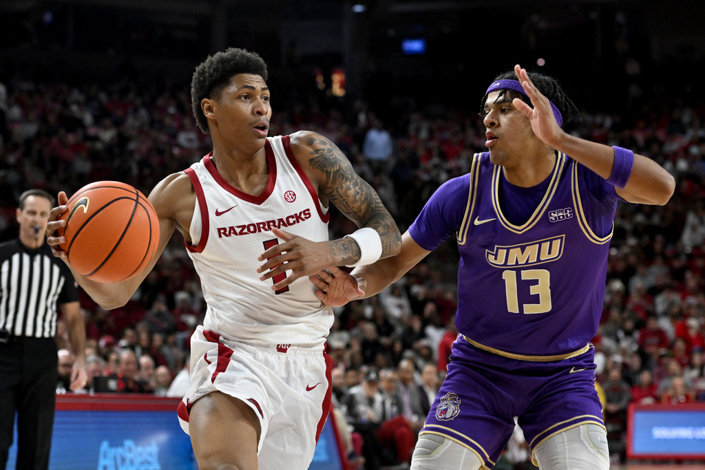 Arkansas guard Meleek Thomas (1) drives past James Madison forward Preston Fowler (13) during an NCAA college basketball game Monday, Dec. 29, 2025, in Fayetteville, Ark. (AP Photo/Michael Woods)