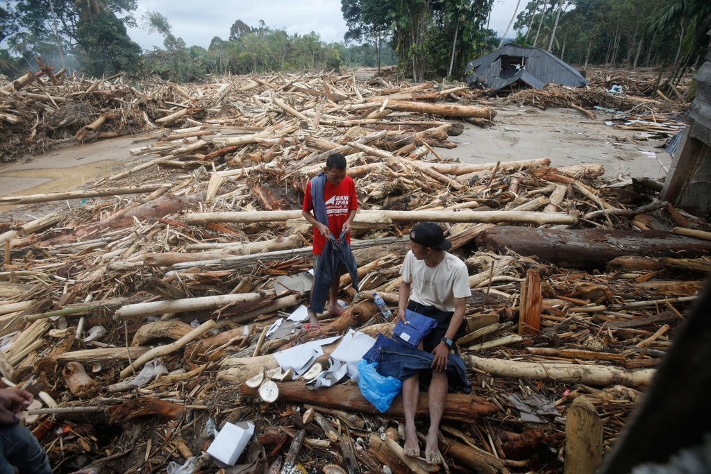 Survivors inspect clothings they salvaged at a village affected by a flash flood in Batang Toru, North Sumatra, Indonesia, Tuesday, Dec. 2, 2025. (AP Photo/Binsar Bakkara)
