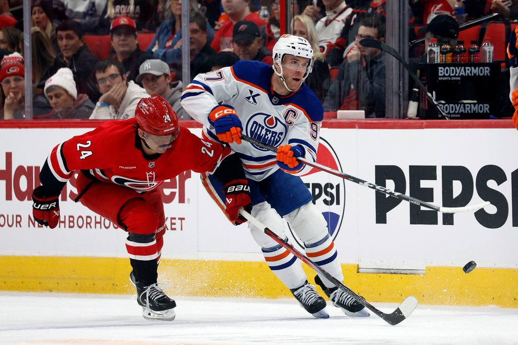 Edmonton Oilers' Connor McDavid (97) avoids Carolina Hurricanes' Seth Jarvis (24) during the first period of an NHL hockey game in Raleigh, N.C., Saturday, Nov. 15, 2025. (AP Photo/Karl DeBlaker)