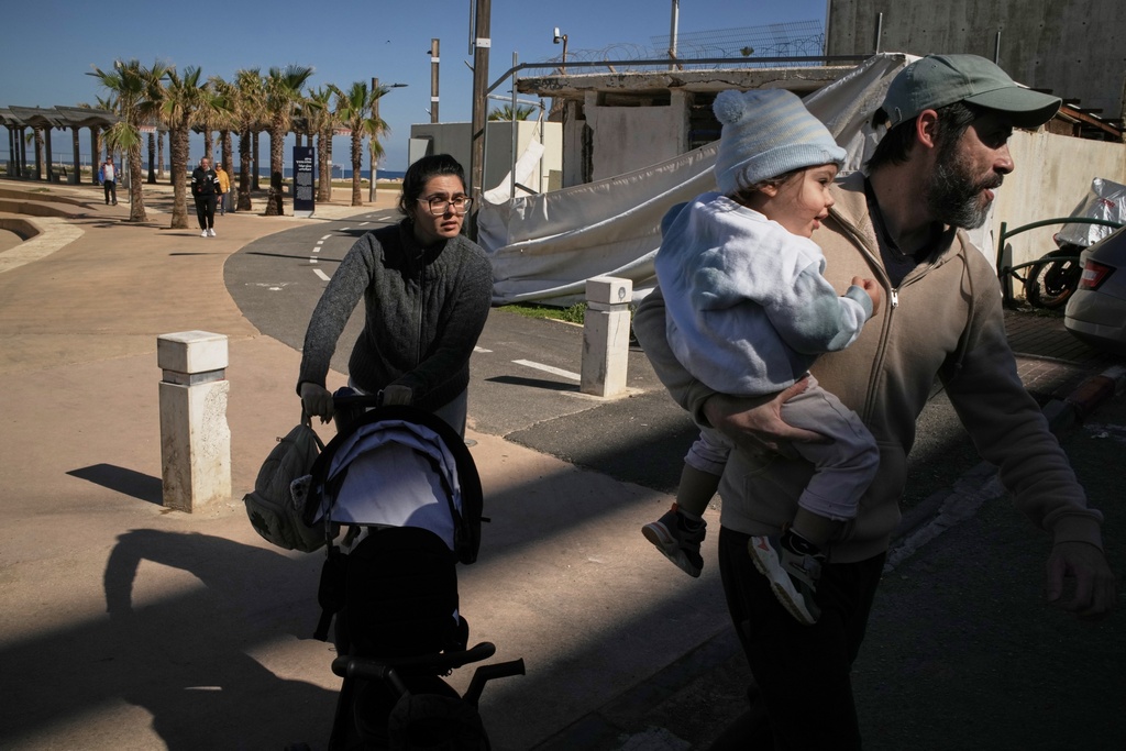 A couple with their two children rush to a shelter after a warning siren sounds following Israeli strikes in Iran, in Haifa, northern Israel, Saturday, Feb. 28, 2026. (AP Photo/Leo Correa)