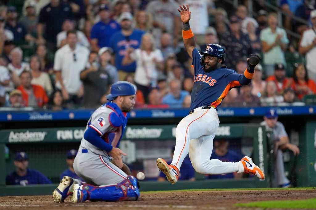 Houston Astros' Taylor Trammell, right, scores as Texas Rangers catcher Austin Wynns handles the throw during the seventh inning of a baseball game Sunday, Aug. 2, 2026, in Houston. (AP Photo/David J. Phillip)