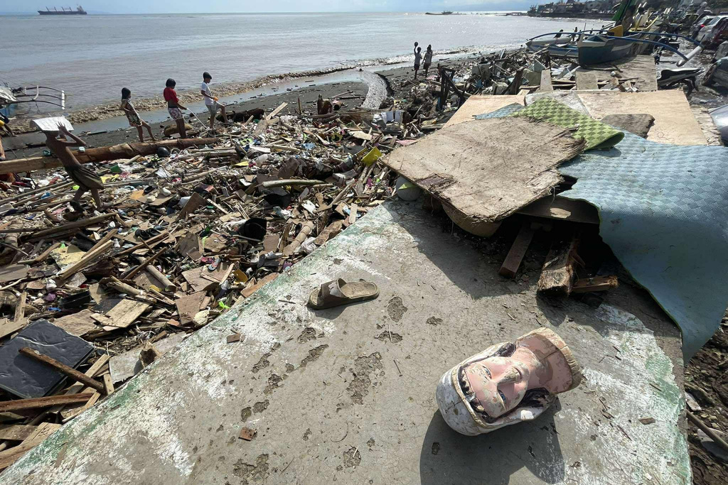 Residents walk along debris along a shoreline after Typhoon Kalmaegi caused devastation in communities at Talisay City, Cebu province, central Philippines, Wednesday, Nov. 5, 2025. (AP Photo/Jacqueline Hernandez)