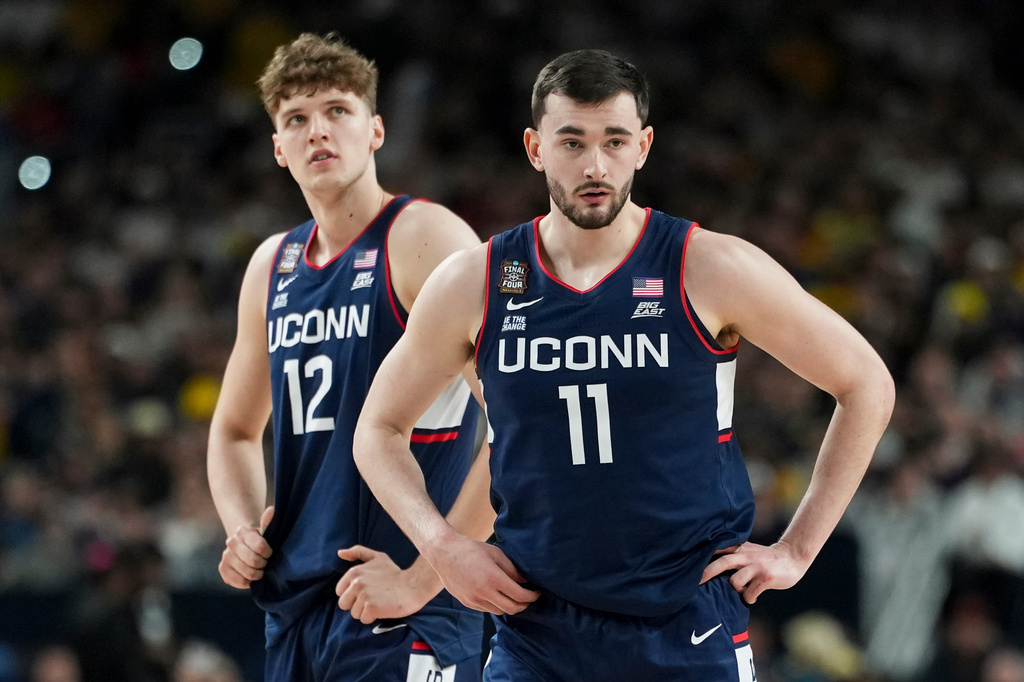 UConn forward Alex Karaban (11) and center Eric Reibe looks towards the bench during the first half of the NCAA college basketball tournament national championship game against Michigan at the Final Four, Monday, April 6, 2026, in Indianapolis. (AP Photo/Abbie Parr)
