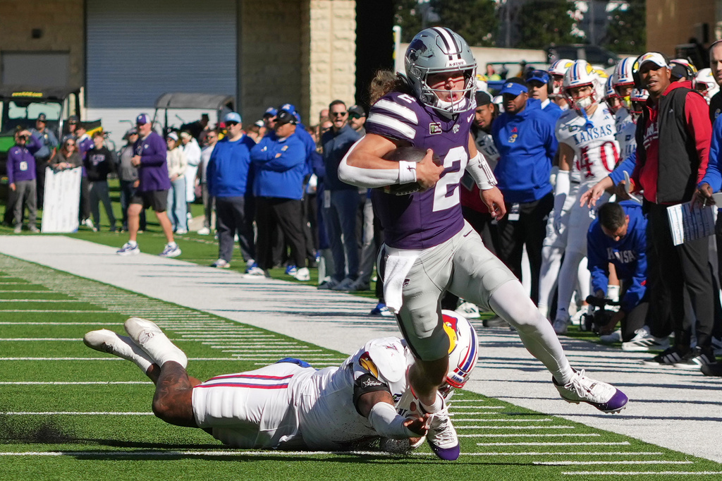 Kansas State quarterback Avery Johnson (2) gets past Kansas linebacker Bam Crouch (7) as he runs the ball during the first half of an NCAA college football game Saturday, Oct. 17, 2026, in Manhattan, Kan. (AP Photo/Charlie Riedel)