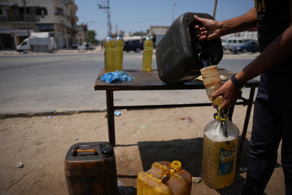 A Palestinian vendor fills bottles with diesel as he offers them for sale in al-Maghazi refugee camp, central Gaza Strip, Saturday, Aug. 15, 2026. (AP Photo/Abdel Kareem Hana)