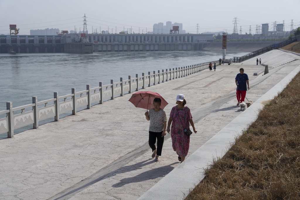 Residents walk along the river bank near Gezhouba Dam, the first dam on the Yangtze River where the wild finless porpoises have been spotted, near Yichang in central China's Hubei province on June 16, 2025. (AP Photo/Ng Han Guan)