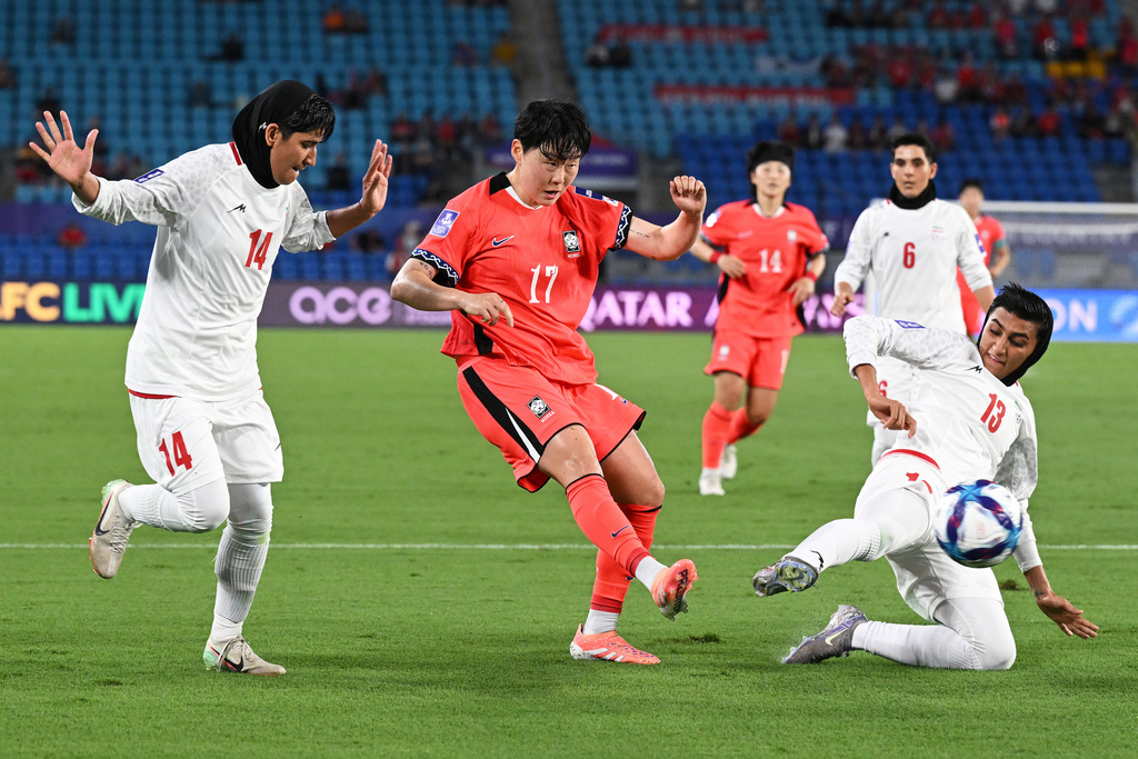 South Korea's Choi Woo-jung, centre, takes a shot on goal as Iran's Fatemeh Makhdoomi, left, and Fatemeh Amineh attempt to block during the Women's Asia Cup soccer match between Iran and South Korea on the Gold Coast, Australia, Monday, March 2, 2026. (Dave Hunt/AAPImage via AP)