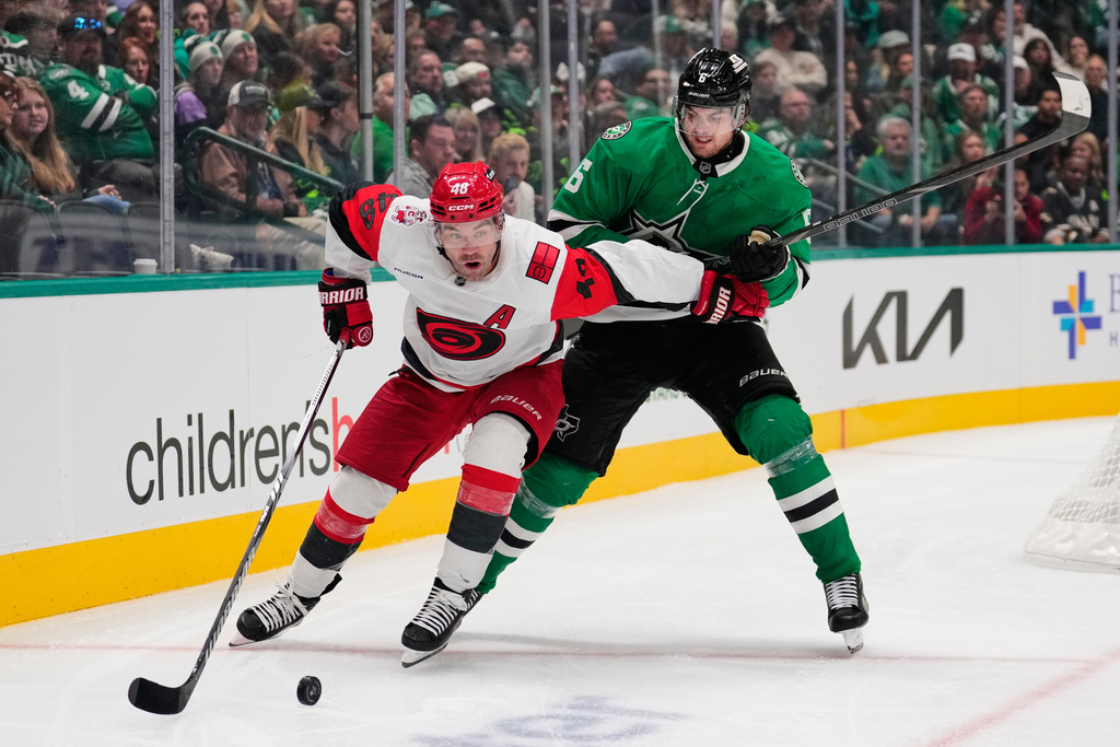Carolina Hurricanes' Jordan Martinook (48) and Dallas Stars' Lian Bichsel compete in the second period of an NHL hockey game Saturday, Oct. 25, 2025, in Dallas. (AP Photo/Tony Gutierrez)