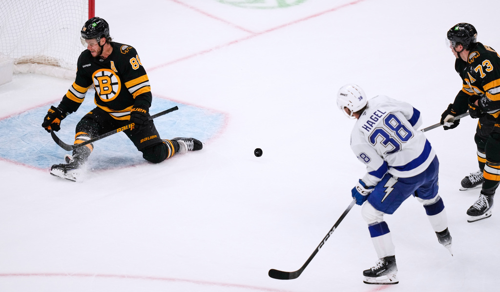 Boston Bruins right wing David Pastrnak (88) makes a save on a shot by Tampa Bay Lightning left wing Brandon Hagel (38), while protecting the empty net, during the third period of an NHL hockey game, Monday, Oct. 13, 2025, in Boston. (AP Photo/Charles Krupa)