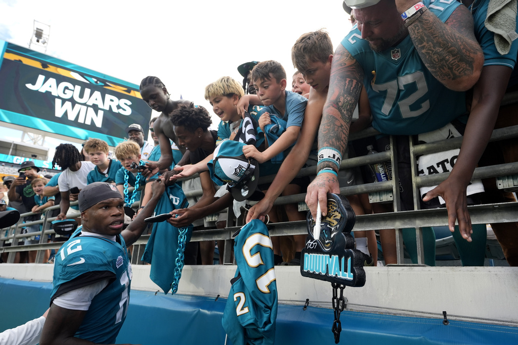 Jacksonville Jaguars wide receiver Travis Hunter (12) gives autographs to fans after an NFL football game against the Carolina Panthers, Sunday, Sept. 7, 2025, in Jacksonville, Fla. (AP Photo/John Raoux)