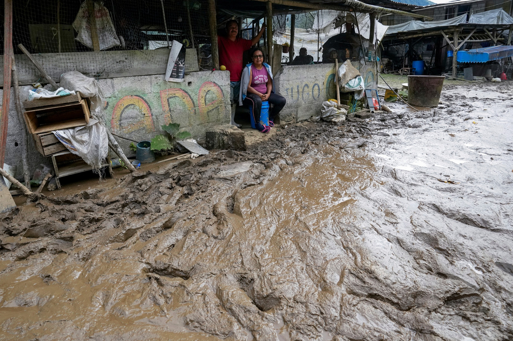 FILE - Residents sit in their houses along a road flooded by a landslide caused by heavy rains in Banos, Ecuador, June 17, 2024. (AP Photo/Dolores Ochoa, File)