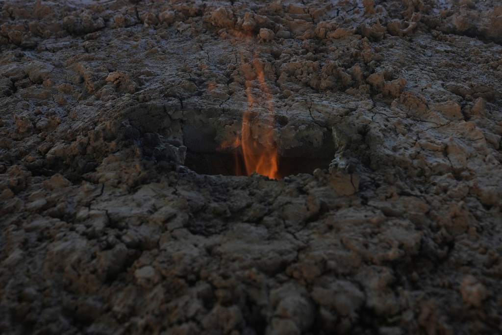 A flame rises from a traditional furnace where mercury ore is heated to turn it into liquid in San Joaquin, Mexico, Tuesday, Aug. 19, 2025. (AP Photo/Fernando Llano)