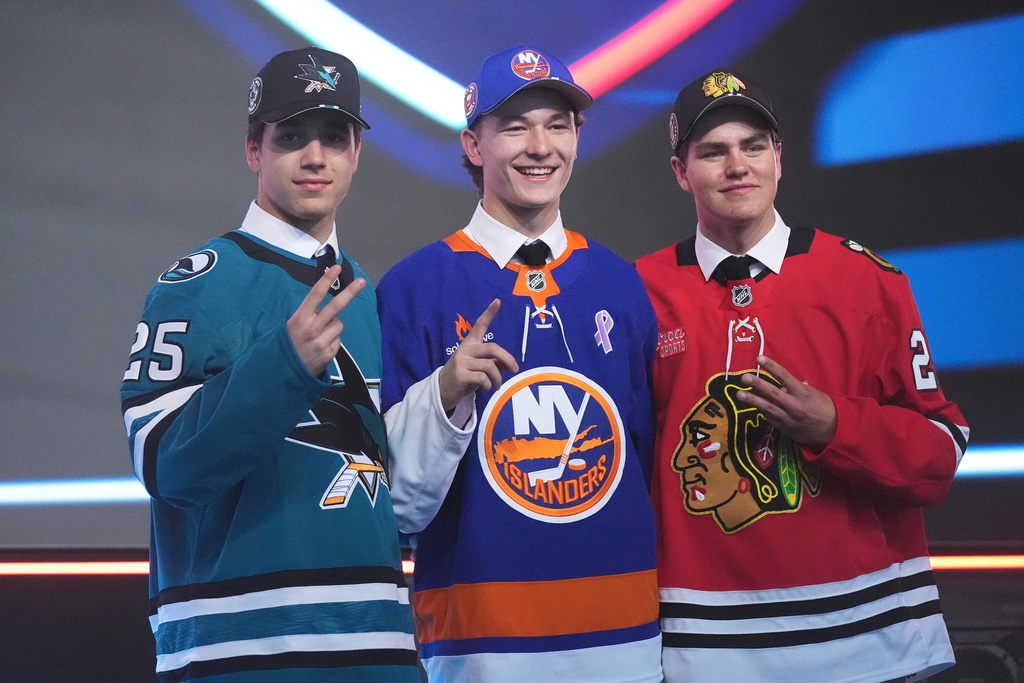 FILE - Matthew Schaefer, drafted first by the New York Islanders, middle, stands between Michael Misa, drafted second by the San Jose Sharks, left, and Anton Frondell, drafted third by the Chicago Blackhawks, during the NHL hockey draft June 27, 2025, in Los Angeles. (AP Photo/Damian Dovarganes, File)