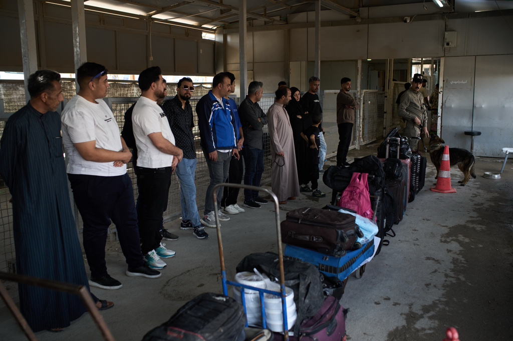 People who arrived from Iran wait in line prior to having their belongings checked by a sniffer dog as they cross the Shalamcheh border crossing between Iran and Iraq, near Basra, Iraq, Sunday, March 29, 2026. (AP Photo/Leo Correa)