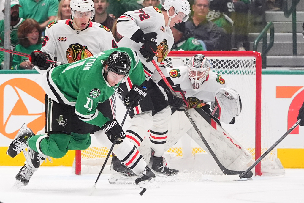 Dallas Stars right wing Nathan Bastian (11) reaches for the puck in front of Chicago Blackhawks defenseman Louis Crevier (46), defenseman Alex Vlasic (72) and goaltender Arvid Soderblom, right, during the second period of an NHL hockey game Saturday, Dec. 27, 2025, in Dallas. (AP Photo/LM Otero)