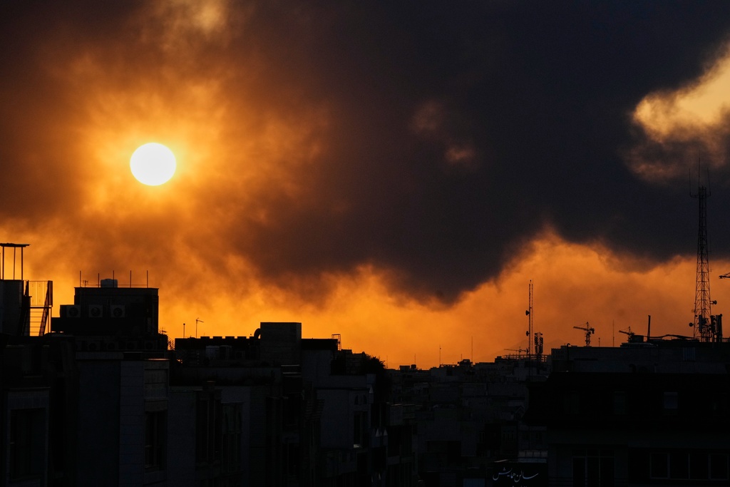 The sun sets behind a plume of smoke rising after a U.S.–Israeli military strike in Tehran, Iran, Tuesday, March 3, 2026. (AP Photo/Vahid Salemi)