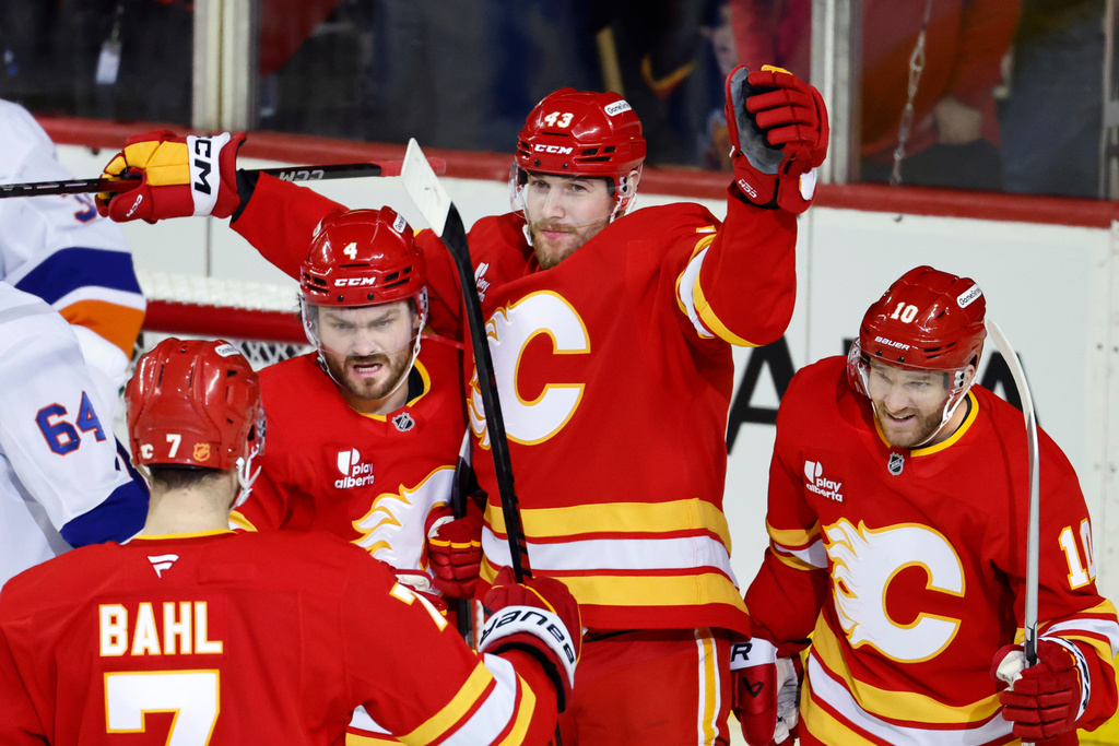Calgary Flames' Adam Klapka, top, celebrates his goal with teammates Rasmus Andersson (4), Kevin Bahl (7), and Jonathan Huberdeau, right, during the second period of an NHL hockey game against the New York Islanders, in Calgary, Alberta, Saturday, Jan. 17, 2026. (Larry MacDougal/The Canadian Press via AP)