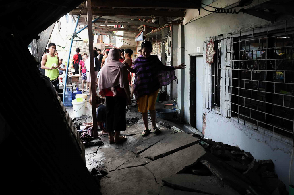 Residents walk along a damaged pathway in General Santos, southern Philippines, Thursday, June 11, 2026, following Monday's powerful earthquake. (AP Photo/Basilio Sepe)