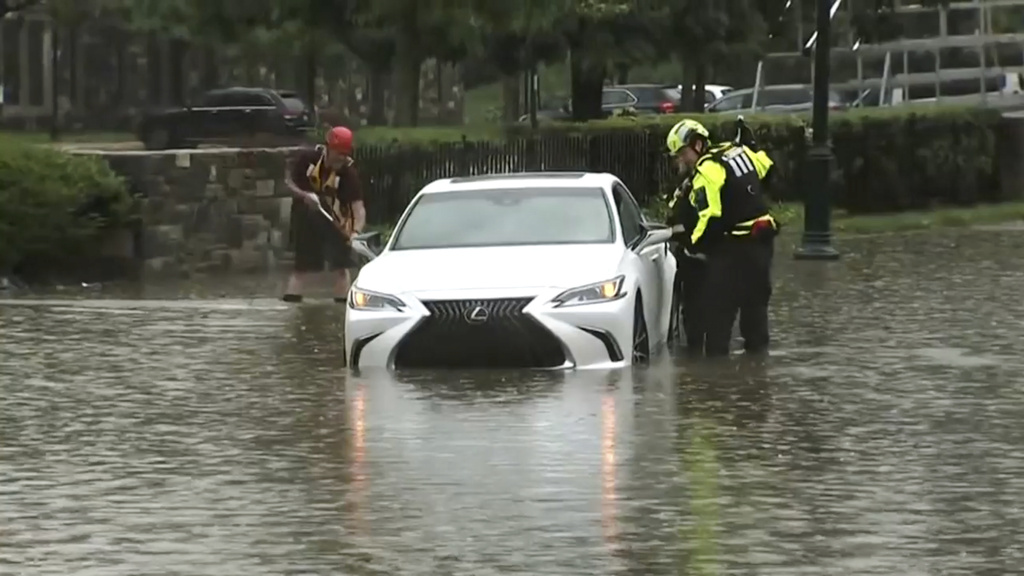 This image taken from video shows authorities inspecting a car lying half-submerged in water on a Philadelphia street on Sunday, July 12, 2026 after a line of severe, short thunderstorms passed through the city the day before. (WPVI-TV/6ABC via AP)