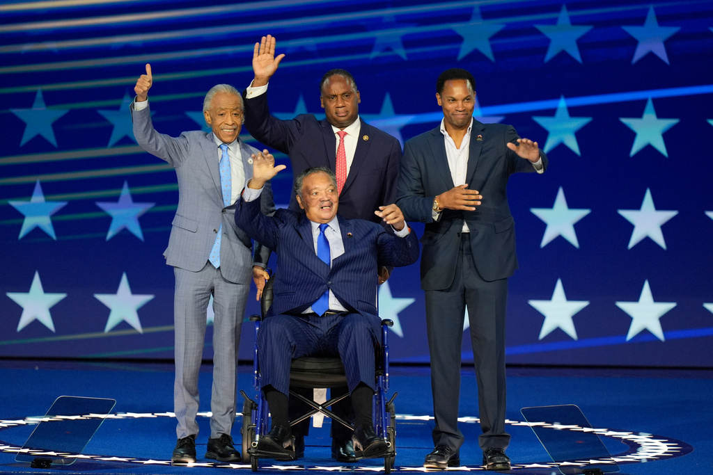 FILE - Rev. Jesse Jackson, center, waves to supporters as he is introduced during the Democratic National Convention, Aug. 19, 2024, in Chicago. With him on stage are Al Sharpton, Jonathan Jackson and Yusef DuBois Jackson. (AP Photo/J. Scott Applewhite, File)