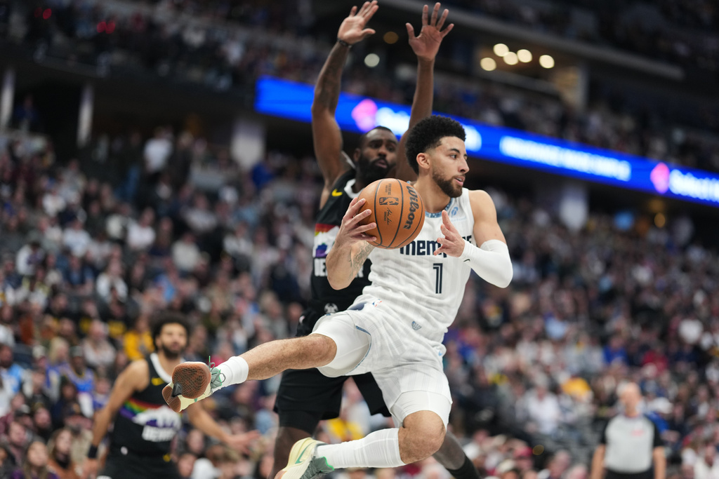 Memphis Grizzlies guard Scotty Pippen Jr., front, passes the ball after driving past Denver Nuggets guard Tim Hardaway Jr. in the first half of an NBA basketball game, Wednesday, Feb. 11, 2026, in Denver. (AP Photo/David Zalubowski)