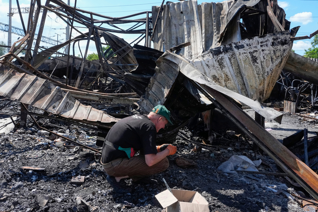 An owner rummages through the ashes on the site of the ruined city marketplace after Russian recent missile attack in Kyiv, Ukraine, Wednesday, June 24, 2026.(AP Photo/Efrem Lukatsky)