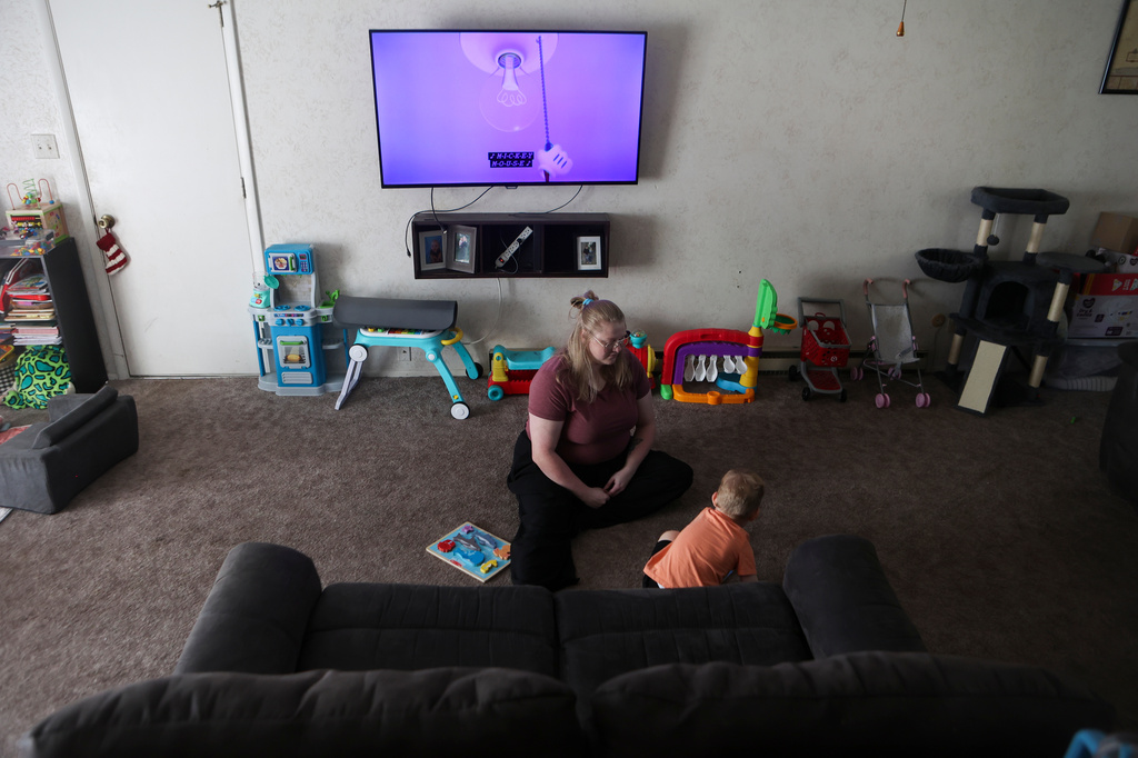 Meygan Maloney does a Mickey Mouse puzzle with her son Callum Wilson, 3, Friday, Aug. 28, 2026, at their home in Hartford City, Ind. (AP Photo/Cara Penquite)