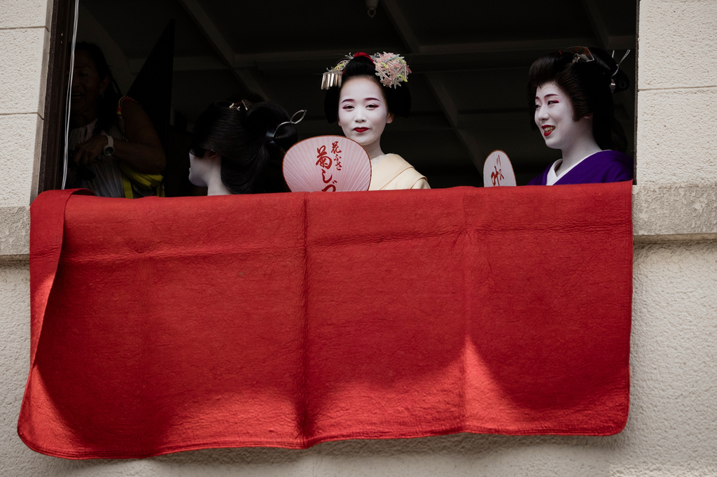 A geiko, a regional word for geisha, and a maiko watch one of the main parades of Shinto's Gion Matsuri festival in Kyoto, western Japan, Friday, July 17, 2026. (AP Photo/Fred Mery)