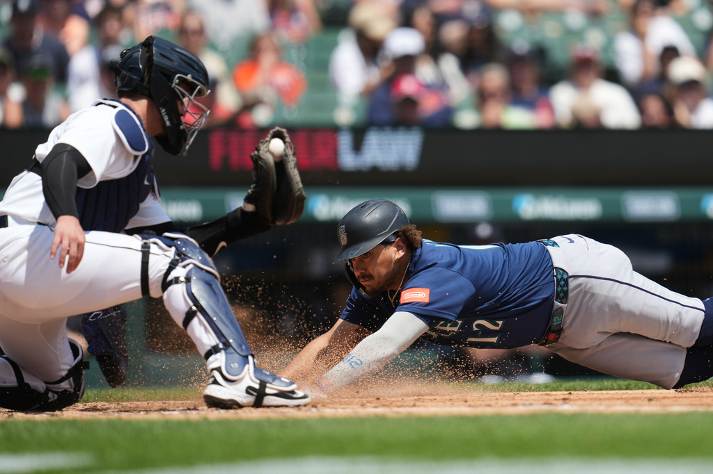 Seattle Mariners' Josh Naylor, right, slides safely into home plate ahead of the tag of Detroit Tigers catcher Dillon Dingler, left, during the third inning of a baseball game Saturday, June 6, 2026, in Detroit. (AP Photo/Paul Sancya)