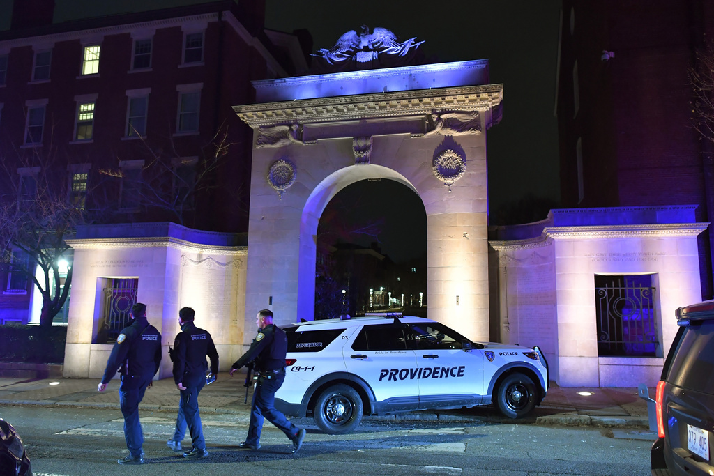 Law enforcement officials walk near an entrance to Brown University in Providence, R.I., on Saturday, Dec. 13, 2025, during the investigation of a shooting. (AP Photo/Steven Senne)
