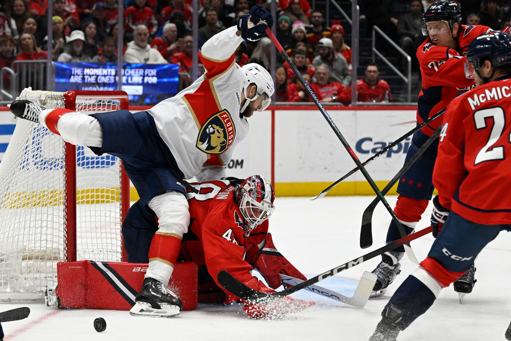 Florida Panthers left wing A.J. Greer (10) falls over Washington Capitals goaltender Logan Thompson during the second period of an NHL hockey game, Saturday, Jan. 17, 2026, in Washington. (AP Photo/John McDonnell)