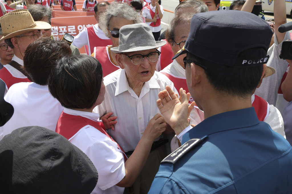 Ahn Hak-sop, center, a 95-year-old former North Korean soldier who spent decades imprisoned in the South, talks with a South Korean police officer near the Unification Bridge which leads to the Panmunjom in the Demilitarized Zone in Paju, South Korea, Wednesday, Aug. 20, 2025. (Im Byung-shik/Yonhap via AP)