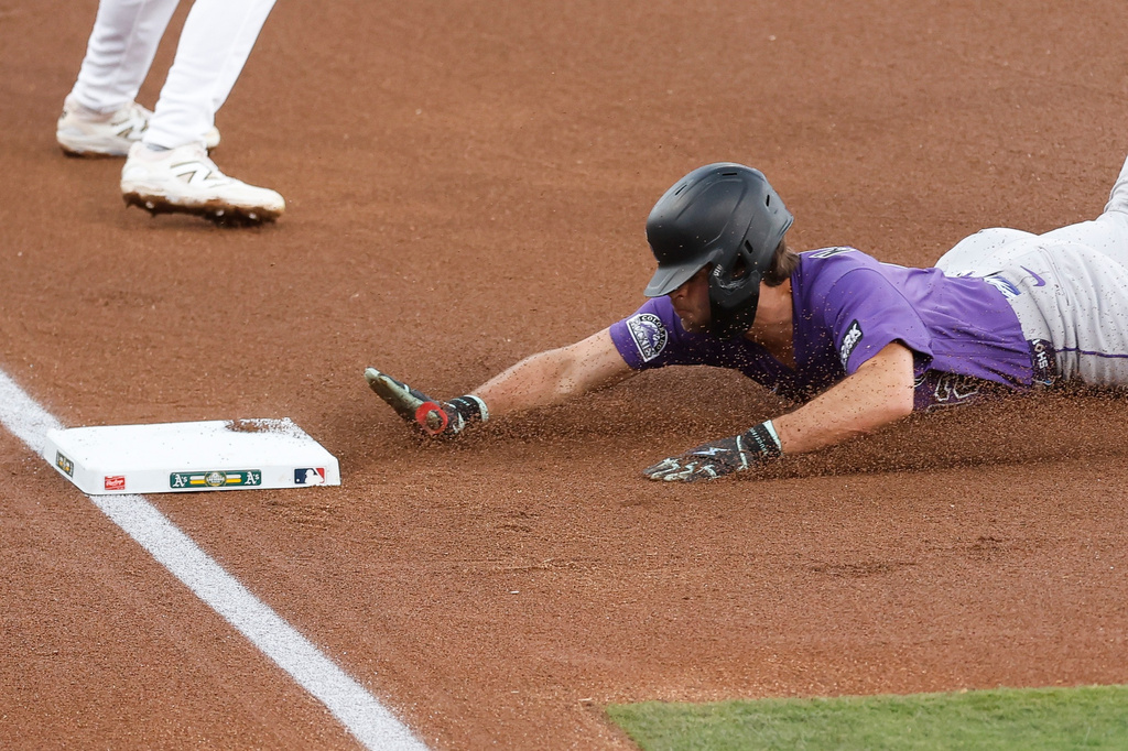 Colorado Rockies' Kyle Karros (12) slides into third base off a single hit by Colorado Rockies first baseman TJ Rumfield (7) during the first inning of a baseball game Friday, June 12, 2026, in Las Vegas. (AP Photo/Caroline Brehman)