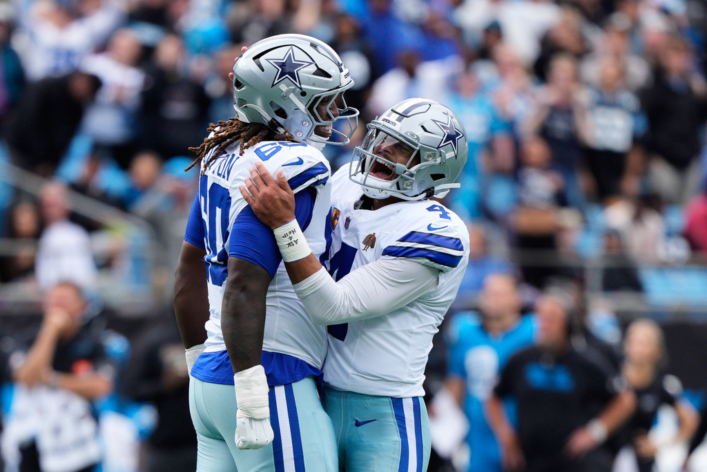 Dallas Cowboys offensive tackle Tyler Guyton (60) and quarterback Dak Prescott (4) celebrate a touchdown in the first half of an NFL football game against the Carolina Panthers, Sunday, Oct. 12, 2025, in Charlotte, N.C. (AP Photo/Jacob Kupferman)