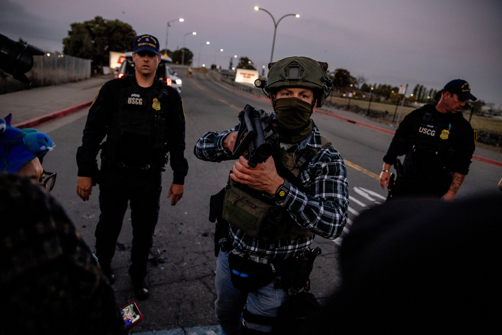 A U.S. Customs and Border Protection agent confronts protesters blocking the entrance to the Coast Guard Island Alameda, where they are sent to as a staging area for the long-threatened immigration crackdown, in Oakland, Calif., Thursday, Oct. 23, 2025. (Stephen Lam /San Francisco Chronicle via AP)