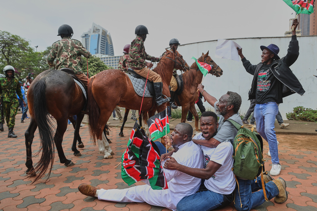 Protesters sing and wave Kenyan flags near Parliament during a demonstration marking two years since the 2024 anti-government protests in Nairobi, Kenya, Thursday, June 25, 2026. (AP Photo/Henry Naminde)